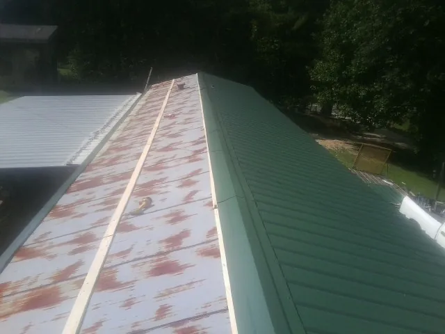 Old rusted panels beside newly installed green metal roofing — Wind Damage Roof Repair by Roofing Brothers in Avon